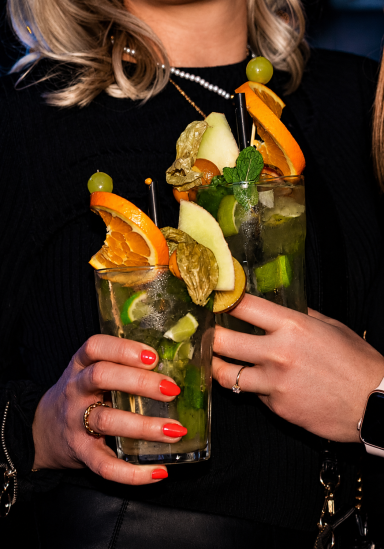 Zwei Cocktails mit Früchten und Kräutern, in Gläsern gehalten. Mojito