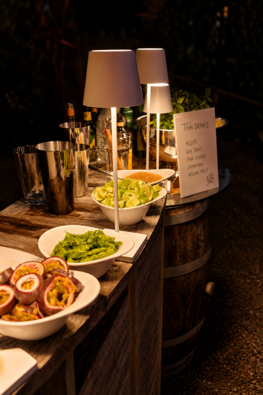 Buffet mit Früchten und Getränke auf einem Holztisch, umgeben von Alkohol.